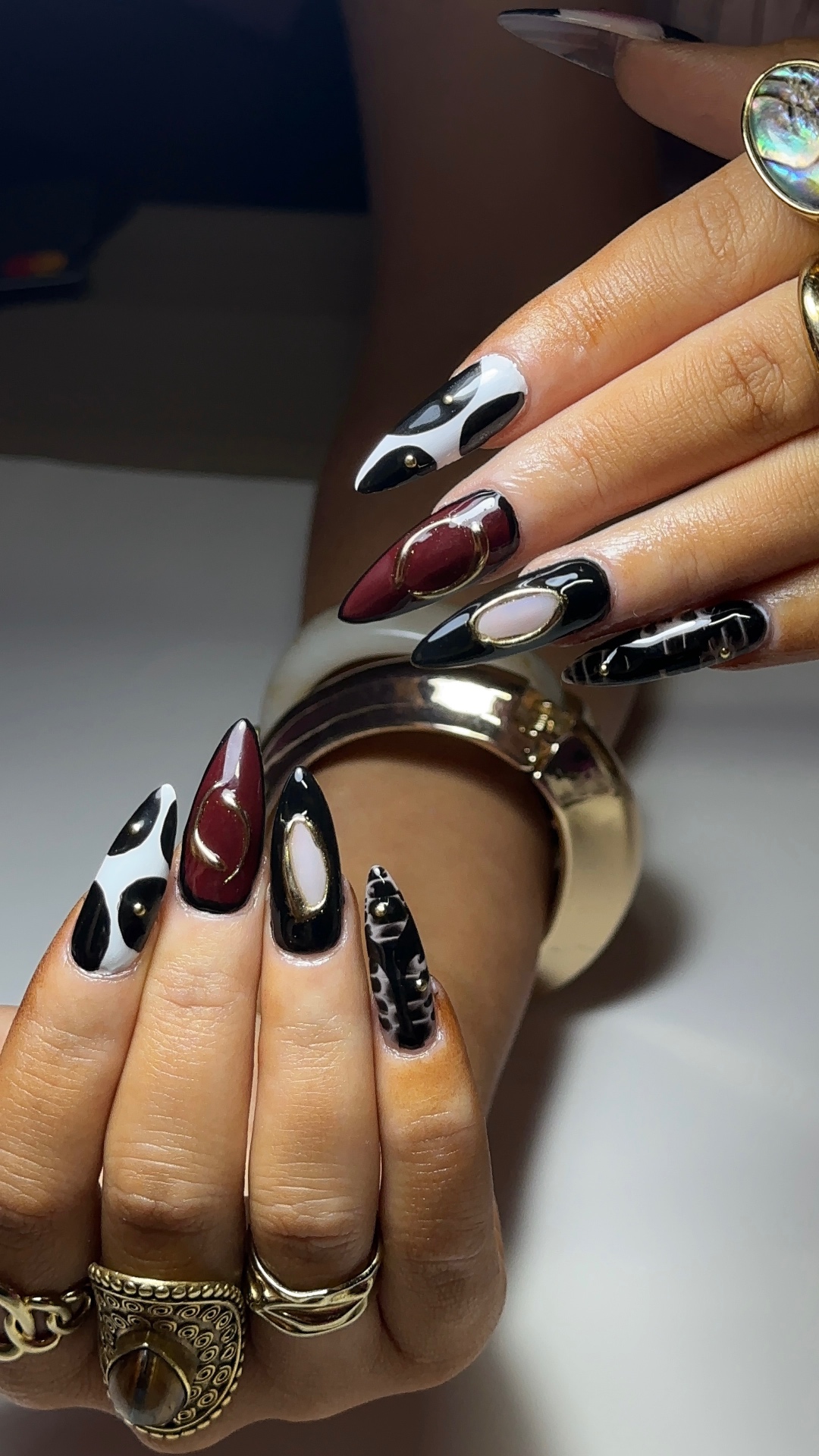 Black, white and burgundy nail art with gold accents