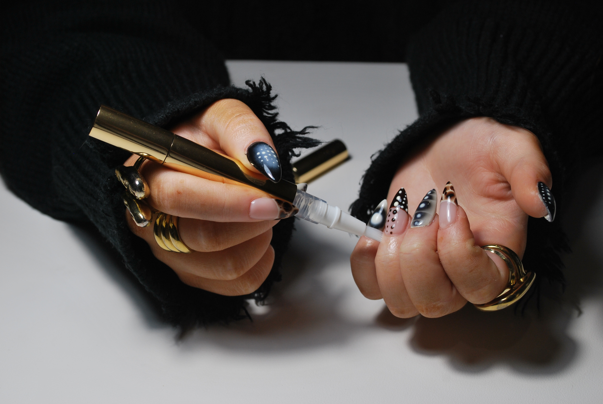 Hands holding a glass cuticle oil dropper bottle in warm light
